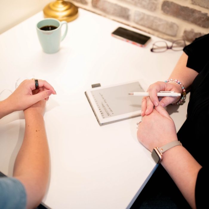 Two people sit at a table, notebook at the ready.