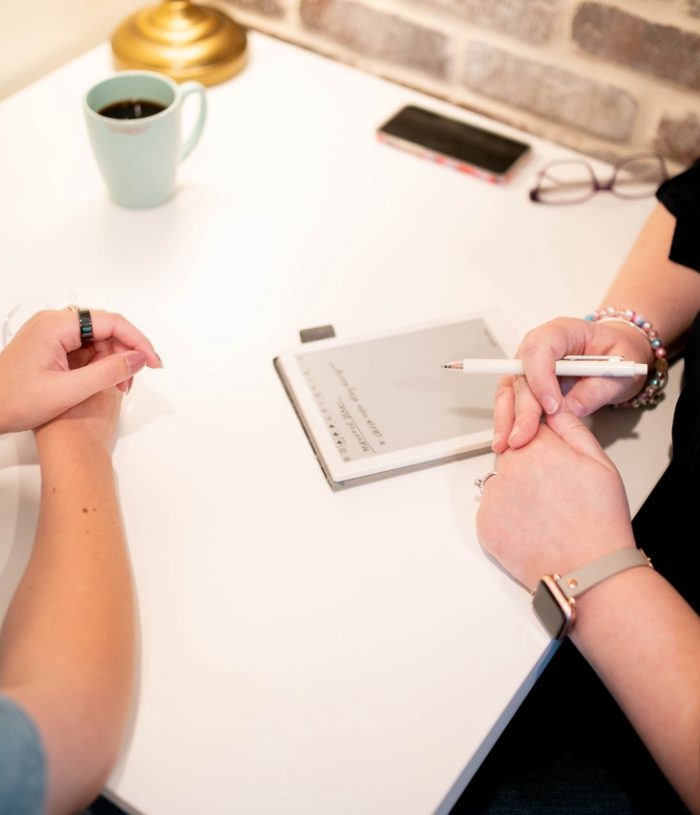 Two people sit at a table, notebook at the ready.